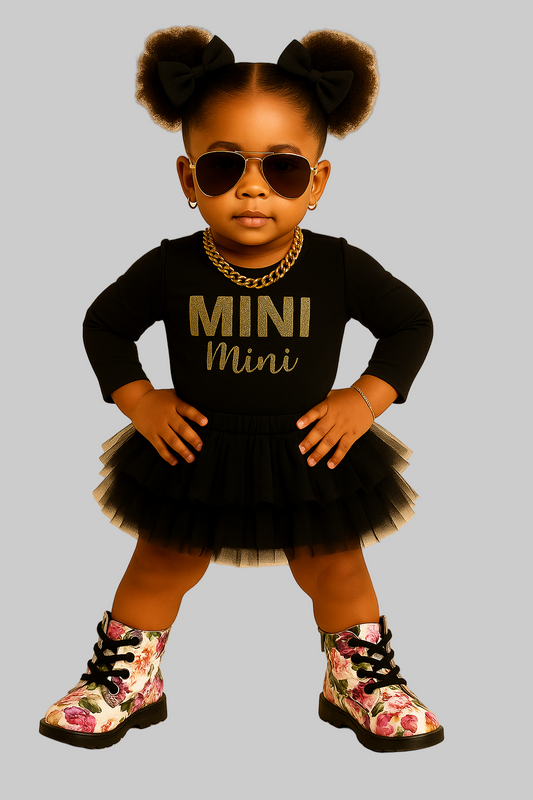 Child wearing a black outfit with 'MINI Mini' text, floral boots, and sunglasses on a beige background