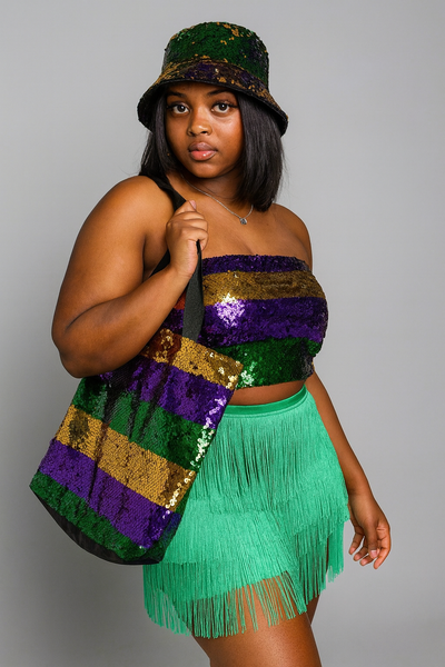 Woman wearing a colorful outfit with a sequined top and green fringe skirt, holding a matching bag.