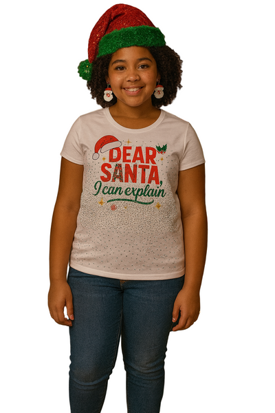 Child wearing a 'Dear Santa I can explain' shirt in front of a decorated Christmas tree.