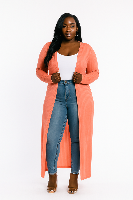 Woman wearing a long coral cardigan, white top, blue jeans, and brown shoes on a white background