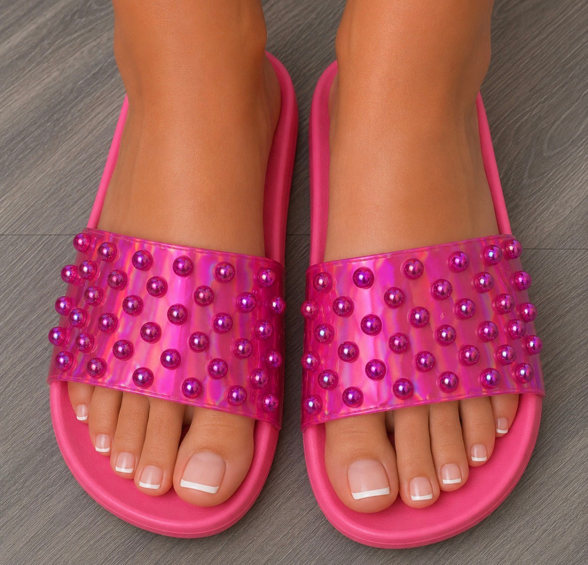 Pink sandals with pearl embellishments on a wooden floor