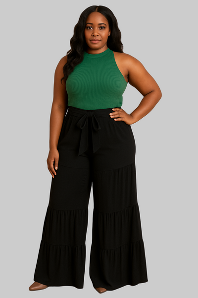 Woman wearing a green halter top and black wide-leg pants on a gray background