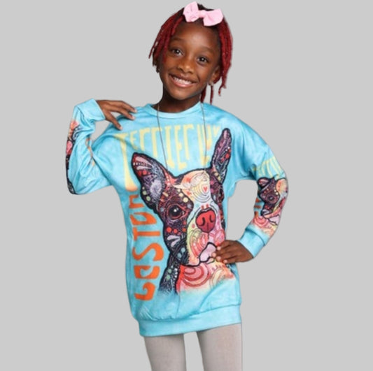 A girl wearing a colorful sweatshirt dress with a graphic design, including the text 'Love' and images of dogs, posing with a smile.