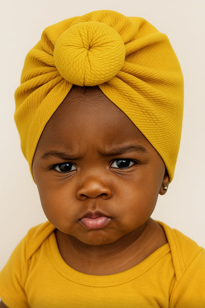Child wearing a yellow turban and matching outfit against a plain background