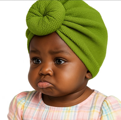Baby wearing a green knotted headband with a white background